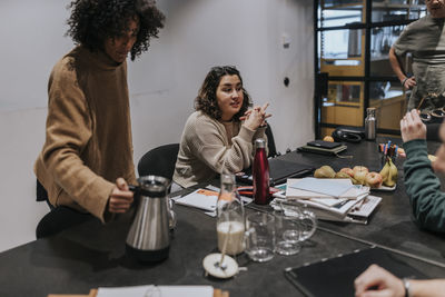 Young businesswoman discussing with colleague during meeting at board room