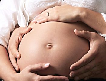 Close-up of man hand embracing pregnant woman belly