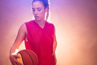 Mid adult woman holding ball while standing against sky