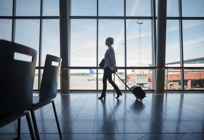 Side view of businesswoman walking with luggage at airport