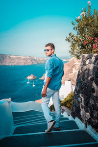 Full length of young man standing against blue sky