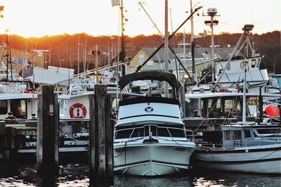 Boats moored at harbor against sky during sunset