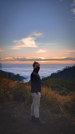 Man standing on field against sky during sunset