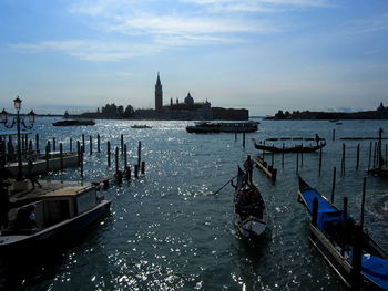 Boats moored in canal with city in background
