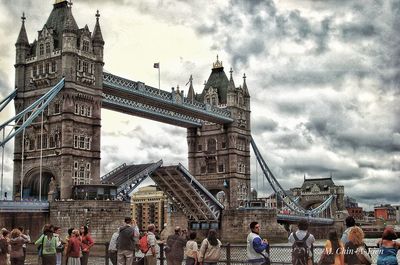 Group of people in front of building against cloudy sky