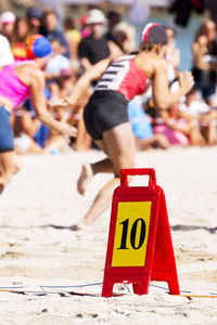 People running on sand by spectators at beach