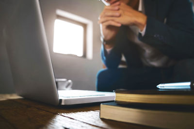 Midsection of businessman using laptop at desk