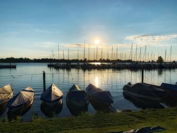 Boats moored in lake against sky during sunset