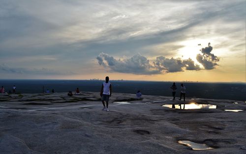 People on beach against sky during sunset