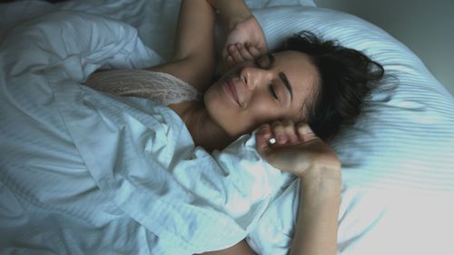 Midsection of woman sleeping on bed