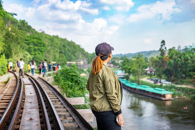 Rear view of man standing on railroad tracks against sky