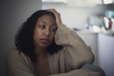 Pensive young woman sitting at home