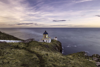 View of lighthouse with sea against sky during sunset