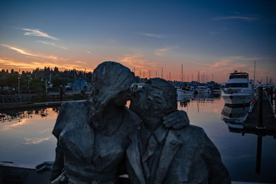 Reflection of man in boat at harbor during sunset