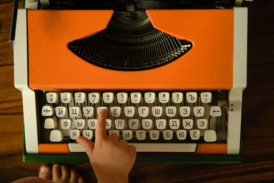 Children's hand presses russian letter on orange vintage typewriter. child learns letters.