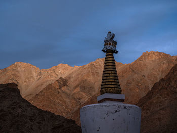 Low angle view of cross on mountain against sky