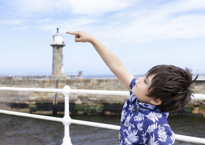 Full length of boy standing by water against sky