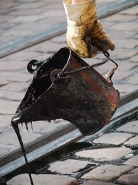 Cropped image of worker pouring tar on railroad track