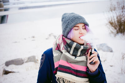 Young woman smoking electronic cigarette during winter