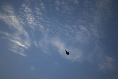 Low angle view of silhouette kite flying against sky