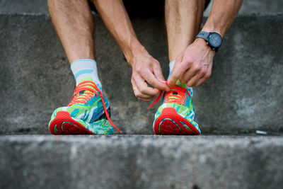 Low section of man tying shoelace