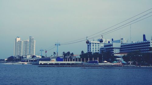 Bridge over river by buildings against clear sky