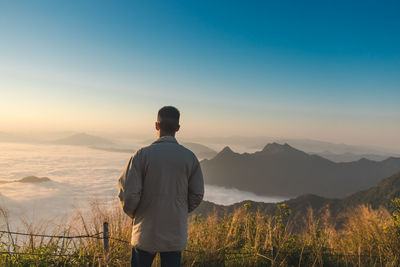 Rear view of man looking at mountains against sky