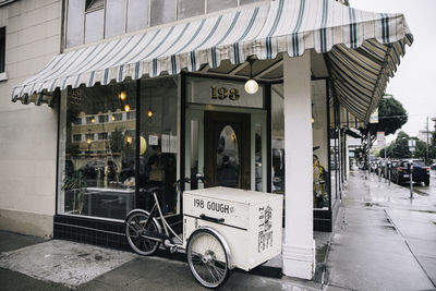 Bicycles on footpath by street against buildings in city