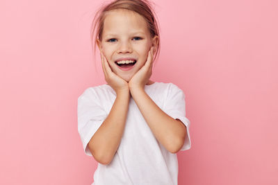 Portrait of smiling cute girl against pink background