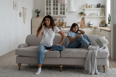 Young woman using phone while sitting on sofa at home