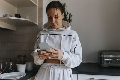 Young woman at home using cell phone