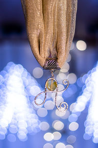 Close-up of hand holding illuminated decoration hanging against blurred background
