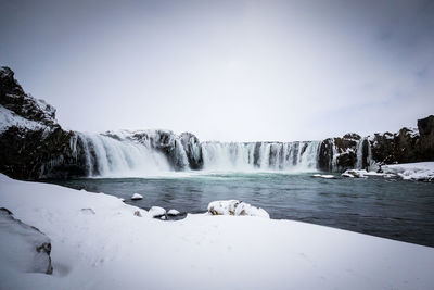 Scenic view of waterfall against sky during winter