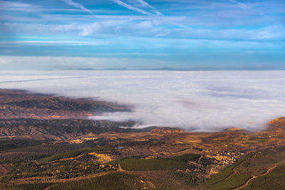 Scenic view of landscape with cloud-filled valley against mountains and blue sky