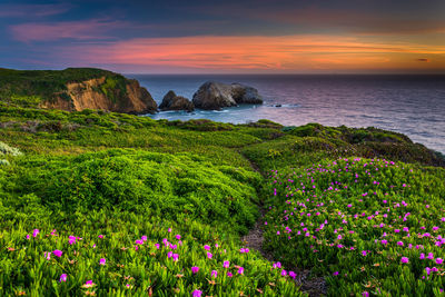 Scenic view of sea and rocks against sky during sunset