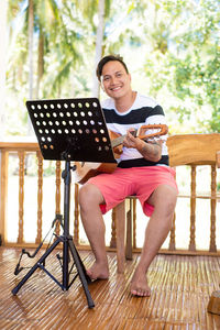 Man holding guitar while sitting on chair