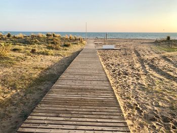 Boardwalk leading towards sea against sky