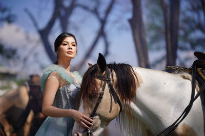 Portrait of a beautiful woman with a horse in the forest background.