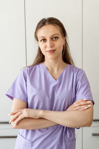 Portrait of young woman standing against wall