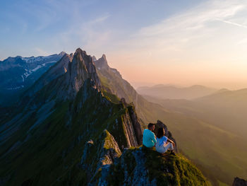 Rear view of people walking on mountain against sky