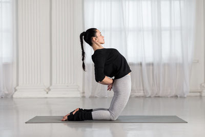 Side view of woman practicing yoga at home