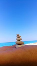 Stack of stones on beach against clear blue sky