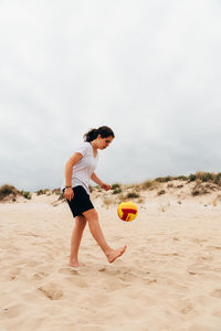 Full length of man playing soccer on beach