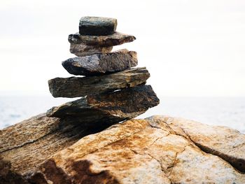 Stack of stones on rocks at beach against sky