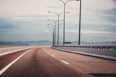 Row of street lights on bridge against sky