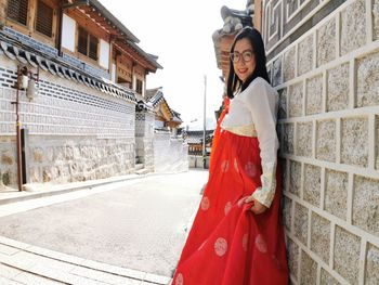 Portrait of woman standing by red building