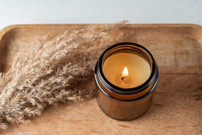 Handmade candle from paraffin and soy wax in glass jar with dry reed grass on wooden tray. candle 