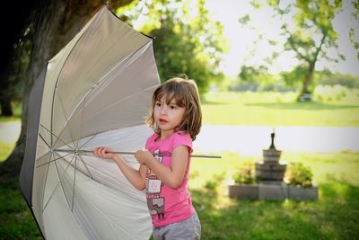 Girl standing on grass against trees