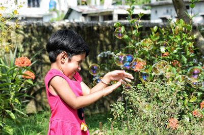 Side view of baby girl standing on flowering plants