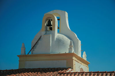 Bell on top of whitewashed dome over rooftop of an old house, in a sunny day at marvao. portugal.